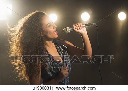 Stock Image - Stage performance of young singer. Fotosearch