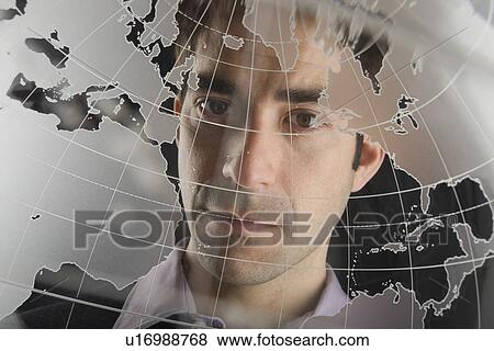 Stock Photo - Studio portrait of man peering through translucent world map. Fotosearch