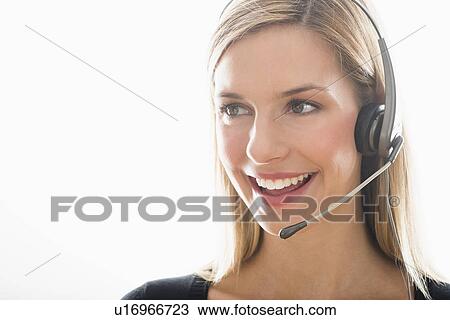 Stock Image - Studio portrait of young woman wearing headset. Fotosearch