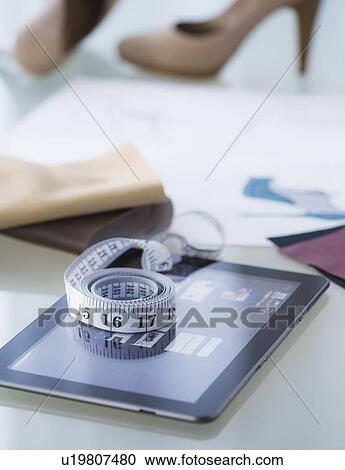 Stock Image - Studio Shot of digital tablet, tape measure and shoes. Fotosearch