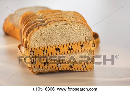Stock Photograph - Studio Shot of measuring tape wrapped around slices of bread. Fotosearch