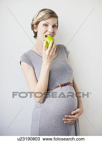 Studio Shot of pregnant woman eating apple View Large Photo Image Stock Image - Studio Shot of pregnant woman eating apple. Fotosearch