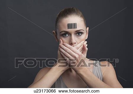 Stock Photograph - Studio shot of young woman covering her mouth. Fotosearch