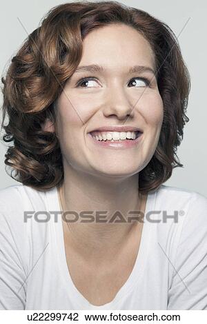 Stock Image - Studio shot portrait of young woman in white blouse. Fotosearch
