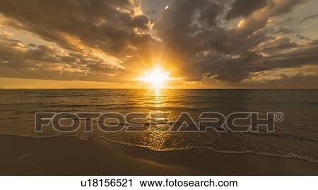 Stock Image - Sun setting over sea. Fotosearch