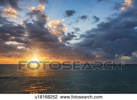 Stock Image - Sun setting over sea. Fotosearch