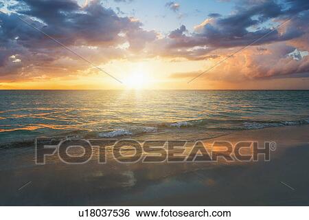 Stock Photograph - Sun setting over sea. Fotosearch