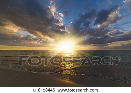 Stock Photograph - Sun setting over sea. Fotosearch