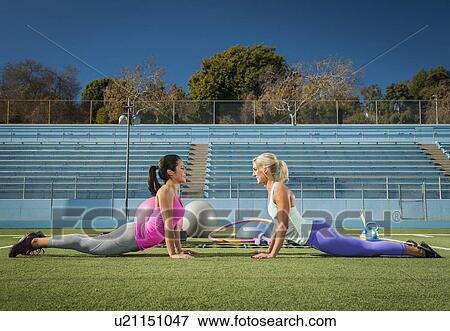 Two women exercising at sports field View Large Photo Image Stock Photo - Two women exercising at sports field. Fotosearch