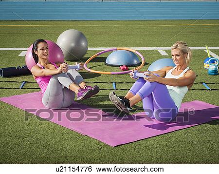 Stock Photograph - Two women exercising at sports field. Fotosearch