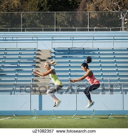 Stock Photo - Two women jumping over hurdles. Fotosearch