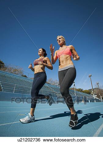 Two women running at sports field View Large Photo Image Stock Photograph - Two women running at sports field. Fotosearch