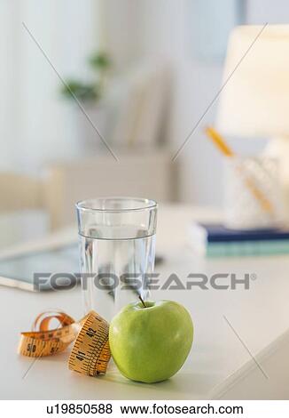 View of glass of water, apple and digital tablet on table View Large Photo Image Stock Photo - View of glass of water, apple and digital tablet on table. Fotosearch