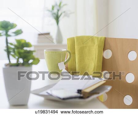 Picture - View of mug, flower pot, mobile phone, key and paper on table. Fotosearch
