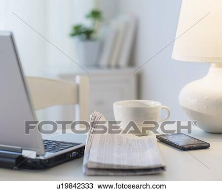 Stock Image - View of newspaper, laptop, mobile phone and cup. Fotosearch