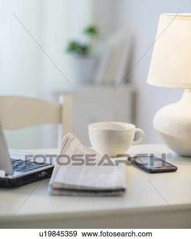 Stock Photo - View of newspaper, laptop, mobile phone and cup. Fotosearch