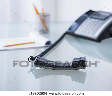 Picture - View of telephone and paper material on desk. Fotosearch
