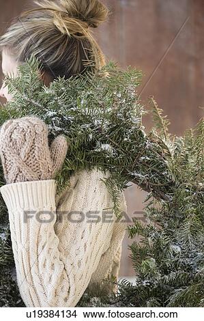 Picture - Woman carrying Christmas wreath. Fotosearch