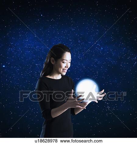 Woman catching glowing ball, studio shot View Large Photo Image Stock Photo - Woman catching glowing ball, studio shot. Fotosearch
