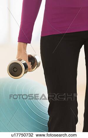 Woman holding dumbbell View Large Photo Image Stock Image - Woman holding dumbbell. Fotosearch
