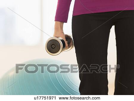 Stock Image - Woman holding dumbbell. Fotosearch