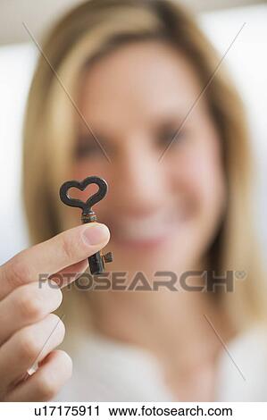 Woman holding heart-shaped key View Large Photo Image Stock Image - Woman holding heart-shaped key. Fotosearch