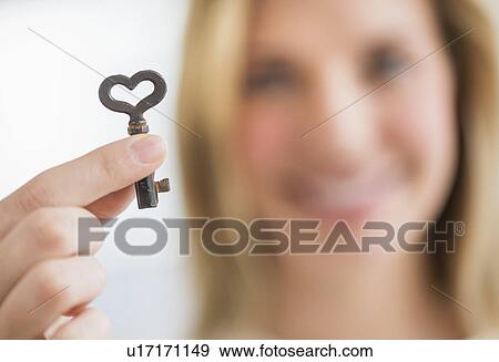Woman holding heart-shaped key View Large Photo Image Stock Photo - Woman holding heart-shaped key. Fotosearch