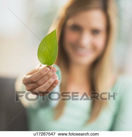 Woman holding leaf, focus on foreground View Large Photo Image Stock Photo - Woman holding leaf, focus on foreground. Fotosearch
