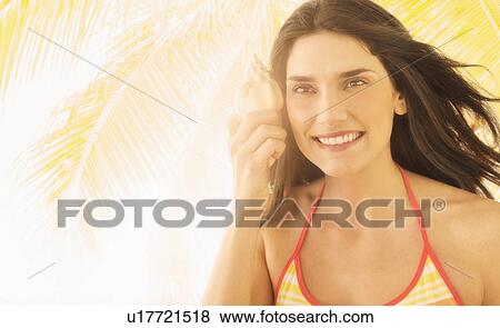 Woman holding shell, palm tree in background View Large Photo Image Stock Photo - Woman holding shell, palm tree in background. Fotosearch