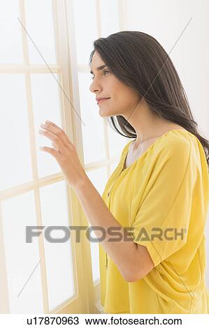 Stock Image - Woman looking through window. Fotosearch