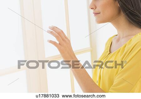 Woman looking through window View Large Photo Image Stock Image - Woman looking through window. Fotosearch