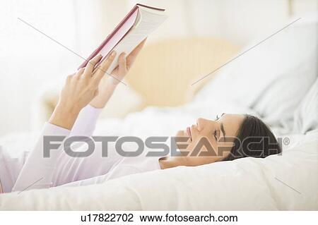Woman lying in bed and reading book View Large Photo Image Stock Image - Woman lying in bed and reading book. Fotosearch