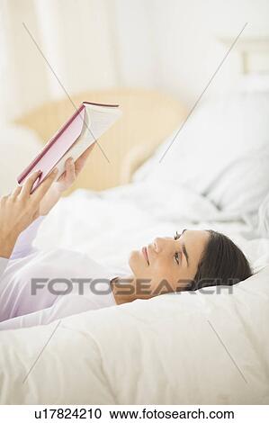 Woman lying in bed and reading book View Large Photo Image Stock Image - Woman lying in bed and reading book. Fotosearch