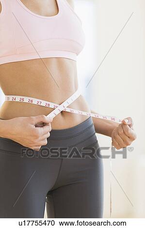 Stock Image - Woman measuring waist. Fotosearch
