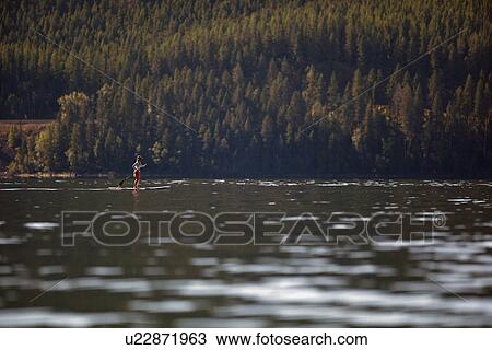Woman paddleboarding on lake View Large Photo Image Stock Image - Woman paddleboarding on lake. Fotosearch