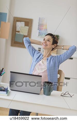Stock Image - Woman relaxing in home office. Fotosearch