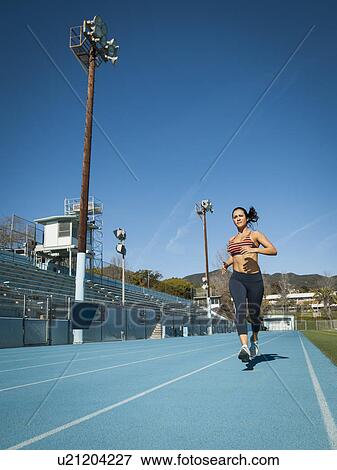 Stock Photo - Woman running at sports field. Fotosearch