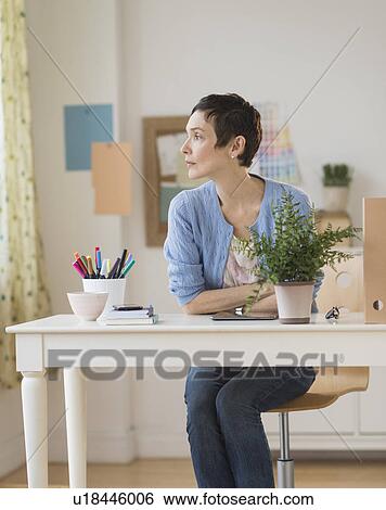 Stock Photograph - Woman sitting in home office. Fotosearch