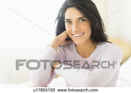 Stock Image - Woman sitting on bed. Fotosearch