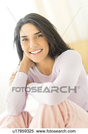 Stock Photography - Woman sitting on bed. Fotosearch