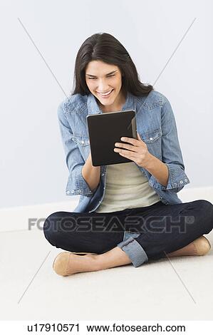 Woman sitting on floor and using digital tablet View Large Photo Image Stock Image - Woman sitting on floor and using digital tablet. Fotosearch