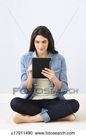Woman sitting on floor and using digital tablet View Large Photo Image Stock Image - Woman sitting on floor and using digital tablet. Fotosearch
