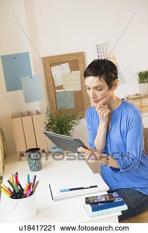 Stock Image - Woman using digital tablet in home office. Fotosearch