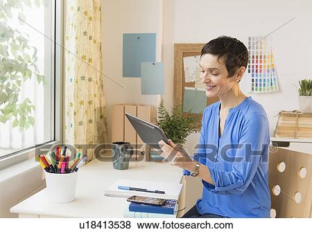 Stock Photo - Woman using digital tablet in home office. Fotosearch