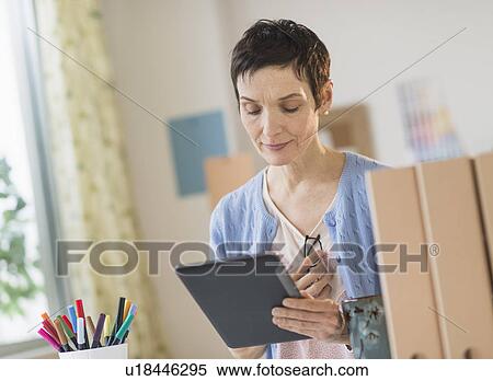 Woman using digital tablet in home office View Large Photo Image Stock Photography - Woman using digital tablet in home office. Fotosearch