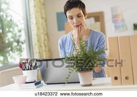 Stock Image - Woman using laptop in home office. Fotosearch