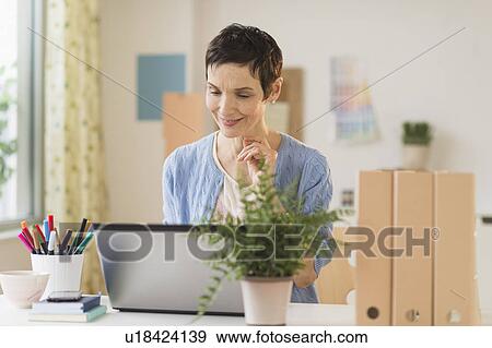 Stock Photo - Woman using laptop in home office. Fotosearch