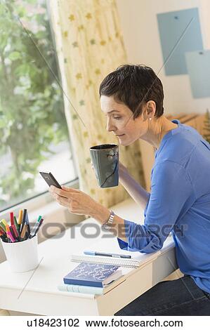 Woman using smart phone in home office View Large Photo Image Stock Image - Woman using smart phone in home office. Fotosearch