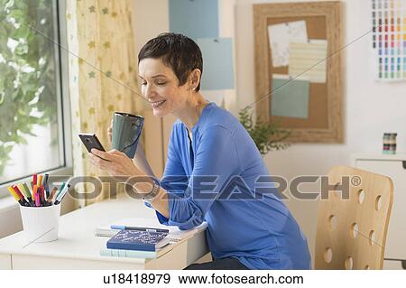 Woman using smart phone in home office View Large Photo Image Stock Photo - Woman using smart phone in home office. Fotosearch