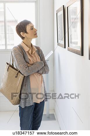 Woman watching photographs in art gallery View Large Photo Image Stock Photo - Woman watching photographs in art gallery. Fotosearch